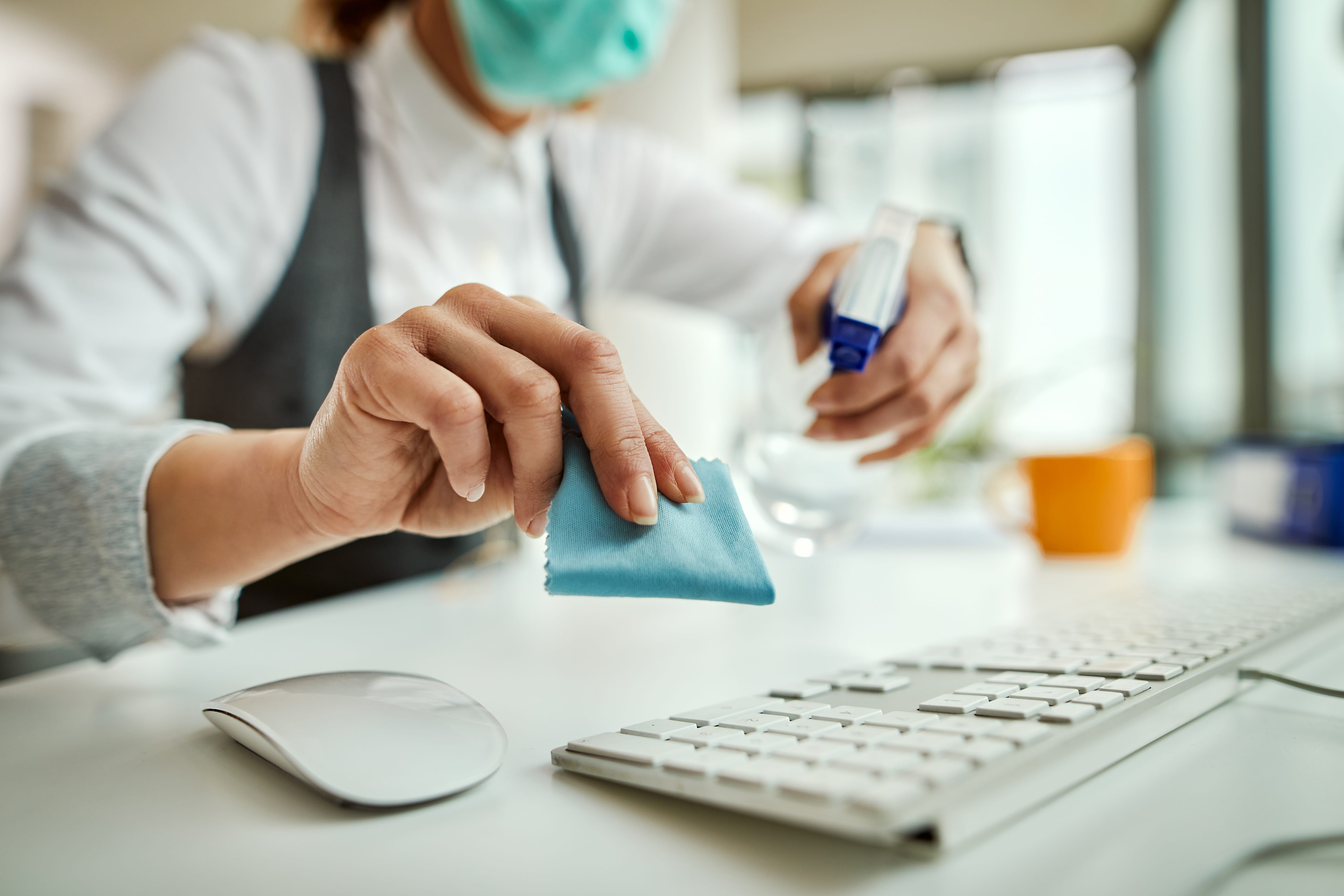 Close-up of businesswoman disinfecting computer keyboard in the Close-up of businesswoman cleaning her computer keyboard in the office.